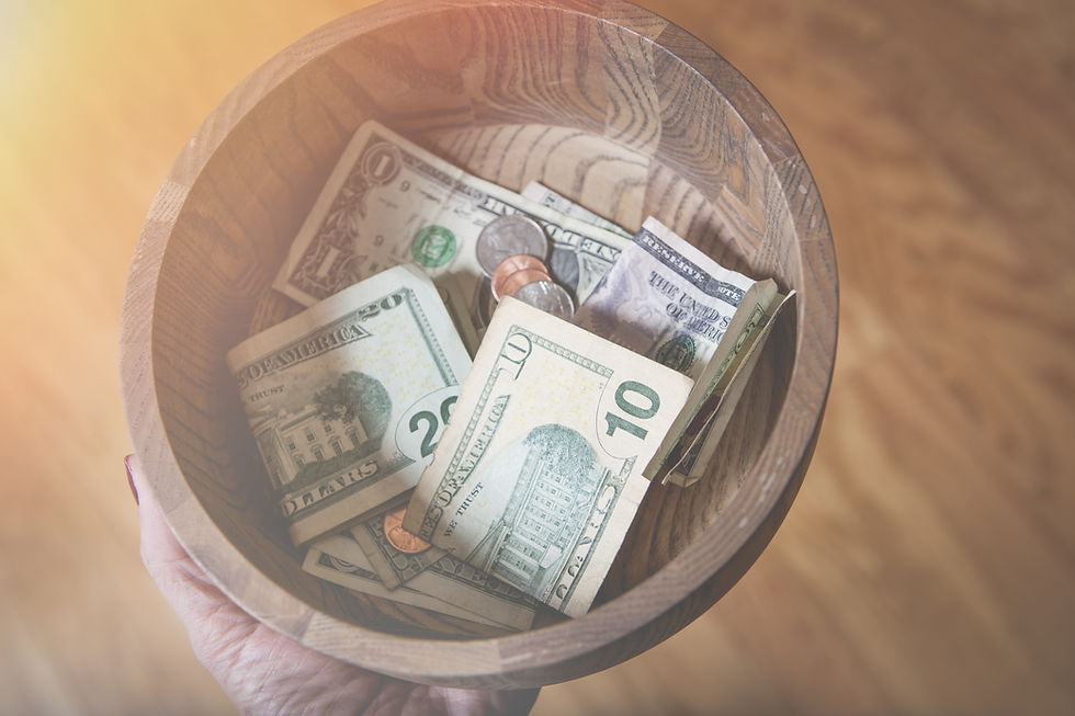 A wooden bowl full of money against a wooden floor